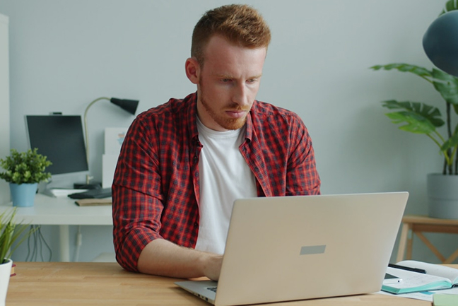 Man in red flannel looking at laptop