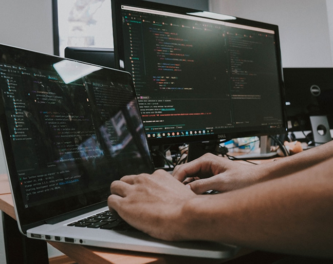 Hands on a laptop and a desktop nearby