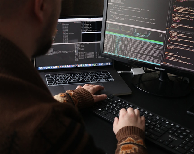 Man looking at a desktop and laptop