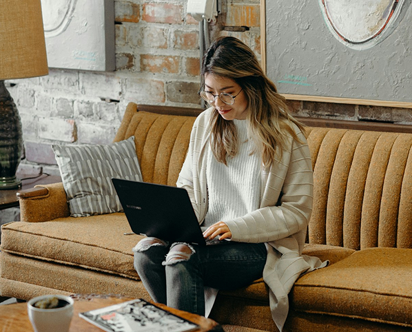 Woman with glasses sitting looking at laptop on lap