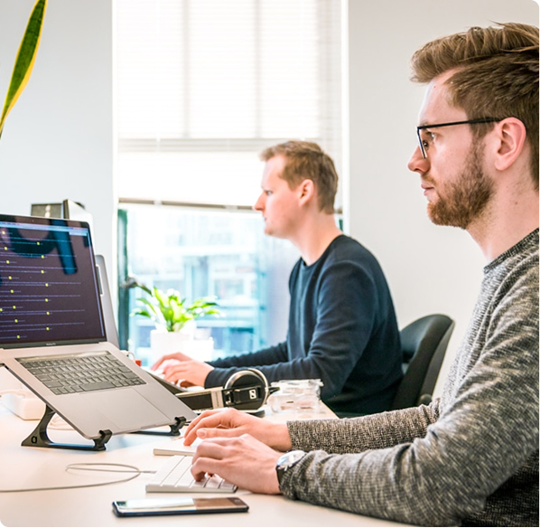 Two men at desk looking at their laptops